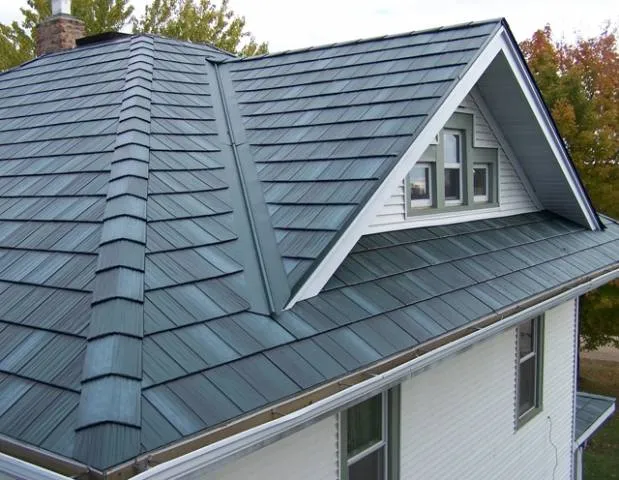 Slate-blue steel shake roofing wraps a gabled dormer above white lap siding on a two-story home.