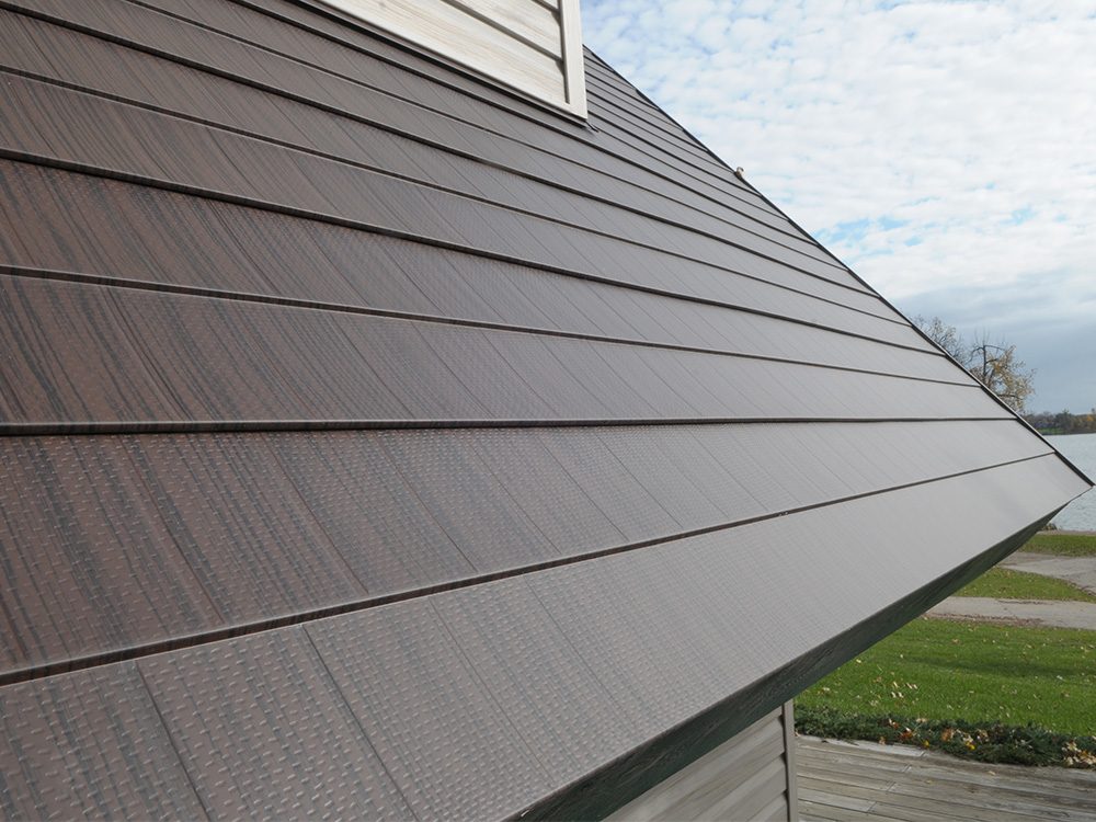 Angled close view of bronze textured steel shake roofing running down a slope toward the eave.