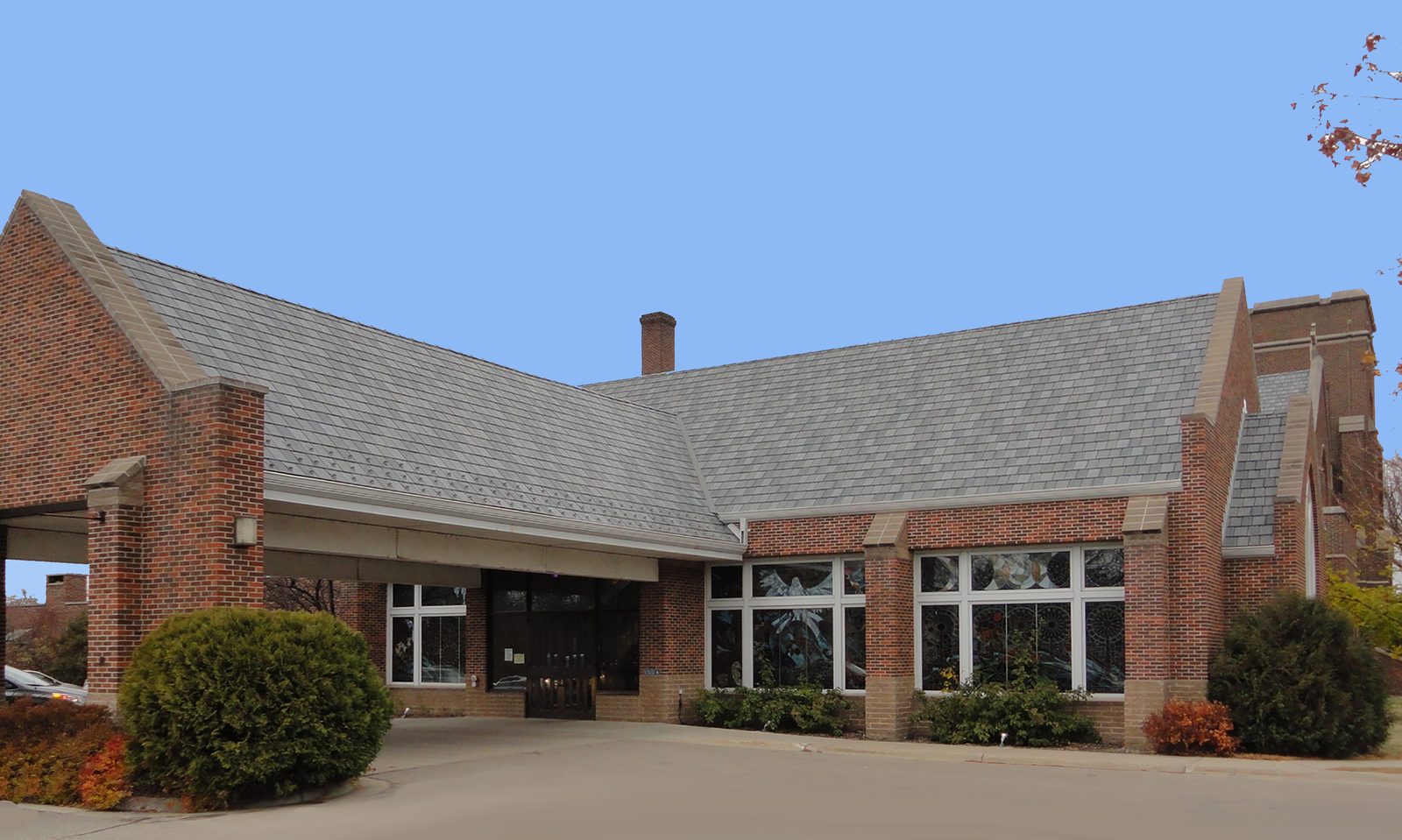 Fresh gray steel shake roofing covers the wide roof of a single-story brick building with a covered entry.