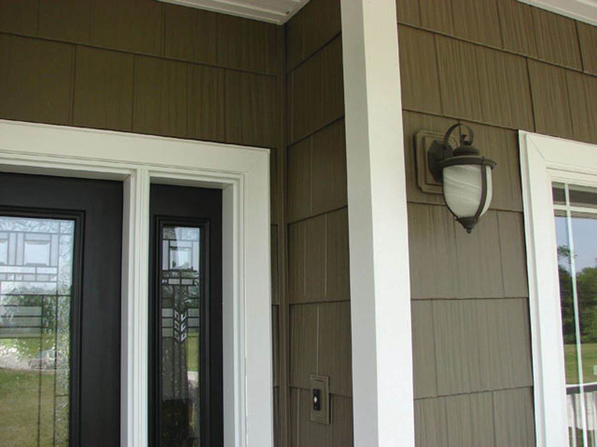 Olive shake-look and vertical steel siding meet at a covered entry beside a lantern sconce.