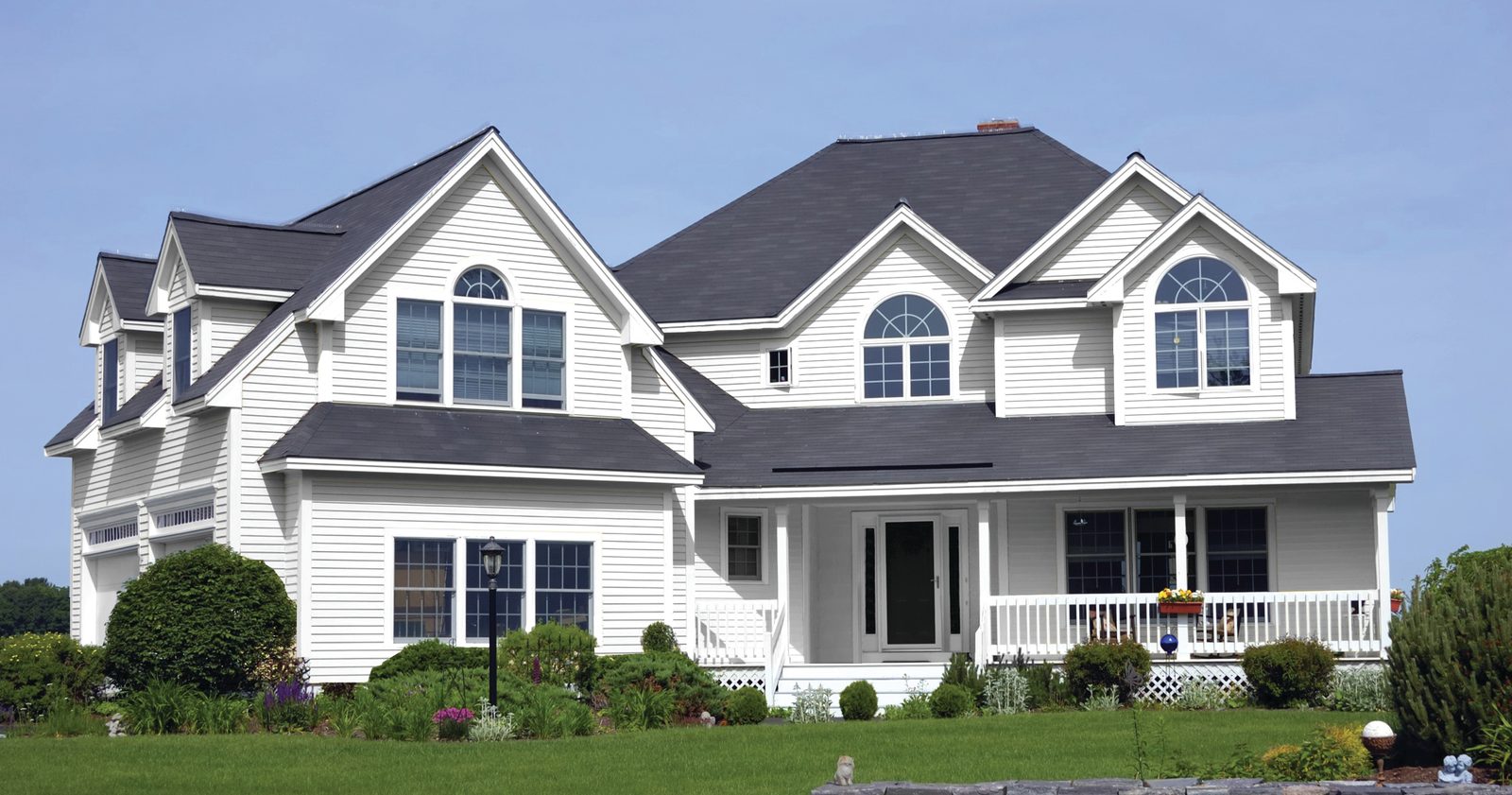 White lap siding covers a large two-story home with multiple gables, dormers and a covered porch.